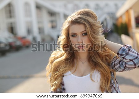 woman outdoor portrait. girl walking in city street. blonde woman with healthy long hair