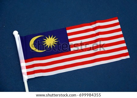 Malaysian flag over blue background Royalty-Free Stock Photo #699984355