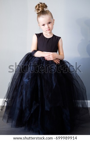 5 year old girl in a black dress on a gray background with a classic hairdo