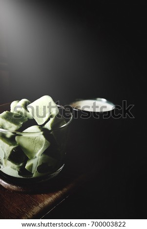 The picture of Matcha latte cubes on glass above wooden table. black background. soft tone color.  selective focus