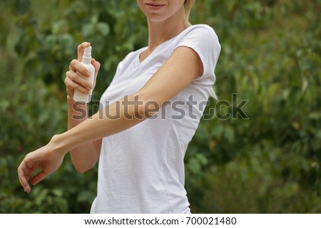 Mosquito repellent. Woman using insect repellent spray outdoors. Royalty-Free Stock Photo #700021480
