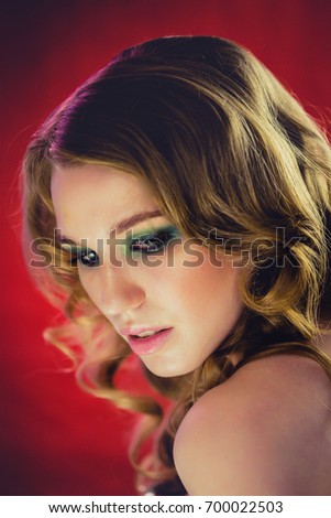 Beautiful young girl with blonde curly hair red background