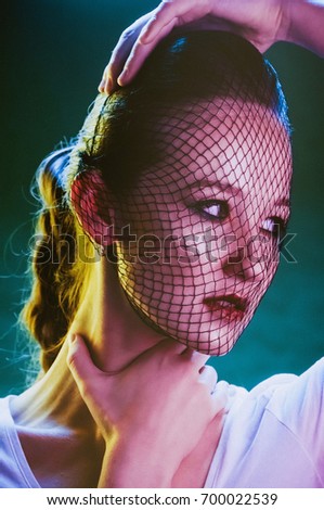 Creative make-up with mesh on girl face and floral decorations color background