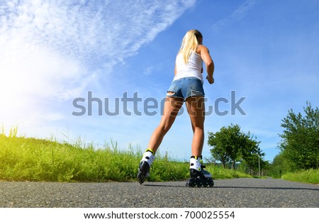 Teenage girl on roller skates at summer. Inline skating on the road.