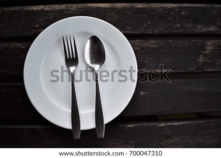 Spoon and fork placed on a white plate.
