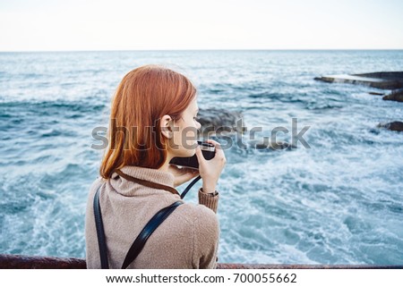 Woman on the sea, camera in her hand takes pictures, nature                               