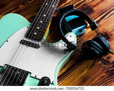 Electric guitar, pedal and headphones on vintage wooden table. Close up.