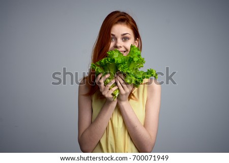 Beautiful woman with lettuce on a gray background                               