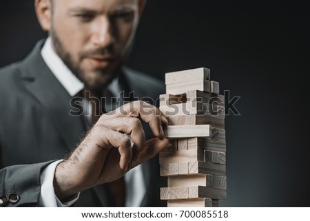selective focus of focused businessman playing blocks wood game isolated on black