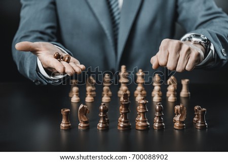 partial view of businessman holding wooden chess figure in hand