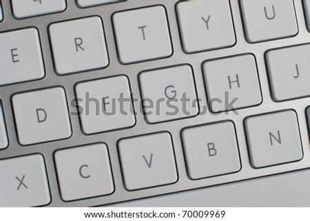 Closeup of a modern aluminum keyboard, focus on center keys.