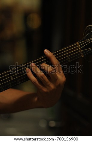 hand with guitar on black background, guitar chords by hand on black background
