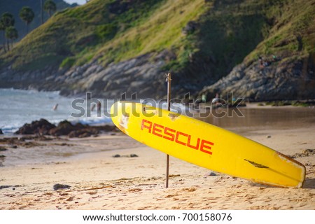 Old yellow survival surfboard, hang on a wooden pole embroidered on the beach, for help drowning people, Lay head to the sea, in a position that can save lives quickly. in case of emergency,save life.