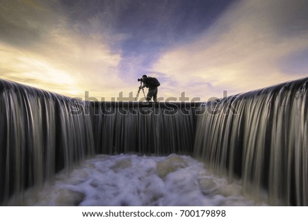 Photographer in action on water flowing in the raceway at sunset in background silhouette