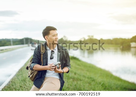 Traveling Asian male tourist backpackers taking photo at park.Travel concept