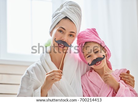 Funny family! Mother and her child with a paper accessories. Mom and daughter preparing for a party and having fun. Beautiful young woman and cute girl with mustache on sticks.