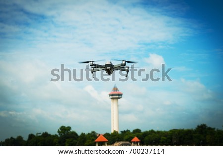 The drone with the professional camera takes pictures of the tower at blue sky. Uav drone copter flying with digital camera. Hexacopter drone with high resolution digital camera on the sky.