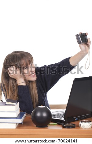 woman sitting at her desk, smiling and taking pictures of herself