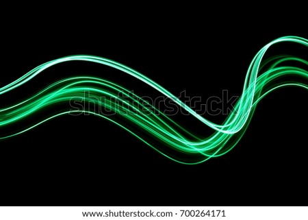 Green light painting photography, long exposure ripples and waves pattern against a black background