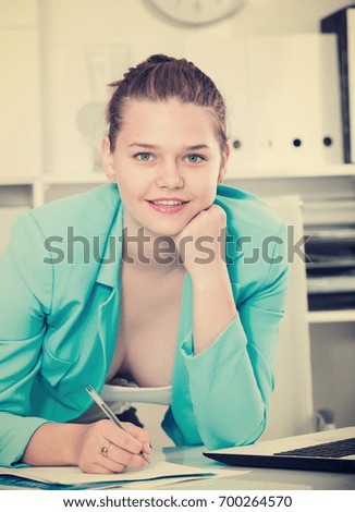 Office worker woman is signing agreement papers of financial nature at office.