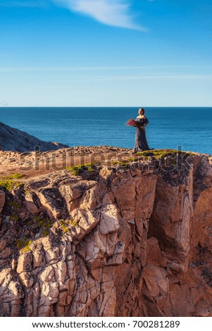 Girl in a dress on the edge of a cliff