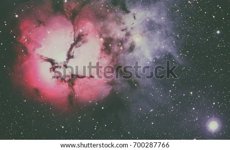 The Trifid Nebula is an H II region located in Sagittarius. An emission nebula, a reflection nebula and a dark nebula. Retouched colored image. Elements of this image furnished by NASA.
