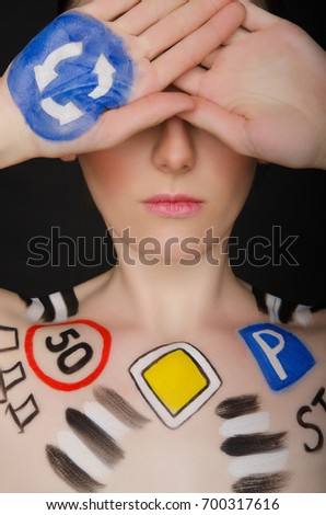 European woman with traffic signs on her body, dark background