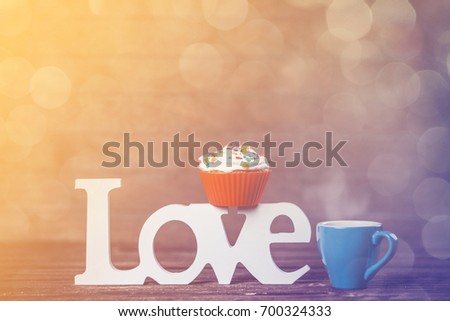 Cupcake, coffee and word Love on wooden table.