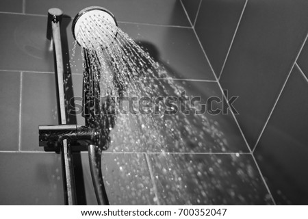 Under the shower jet/Image taken from below of a shower spraying water jets inside a bathroom bathtub.