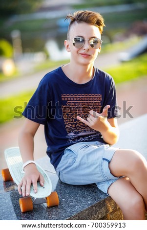 A teenager in sunglasses skates on a skateboard. The boy is in the city. Guy with sunscreens. Skateboarding