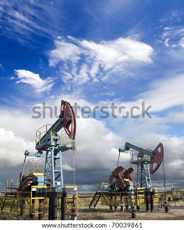 Oil and gas industry. Work of oil pump jack on a oil field. White clouds and blue sky