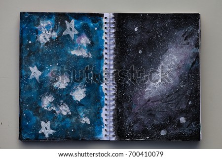 An old calendar has been made into an art journal. It is used to test and practice different techniques. A spread where two different techniques have been used to paint a galaxy.