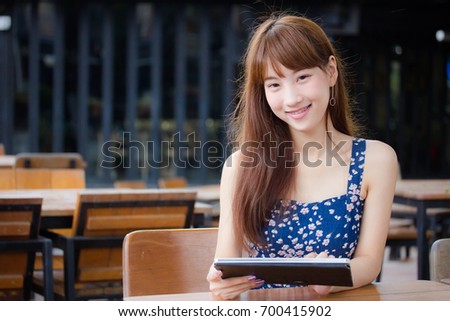 Beautiful young adult thai japanese using her tablet.