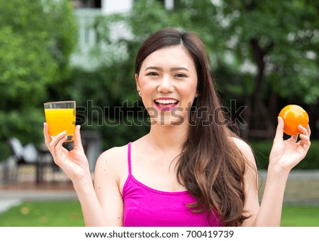 Young beautiful asian woman eating/drinking orange/orange juice fruits, healthy eating with clean food and fruit for diet contact