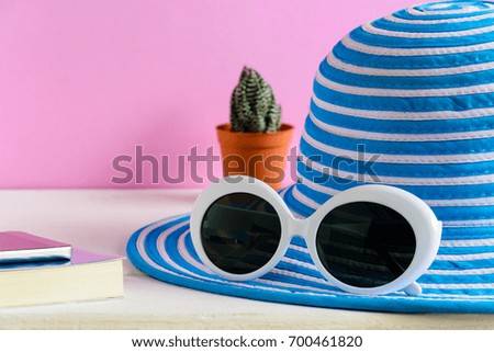 Blue hat and white sunglasses pink wall background with travel and fashion style
