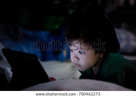 asian children watching tablet on bed

