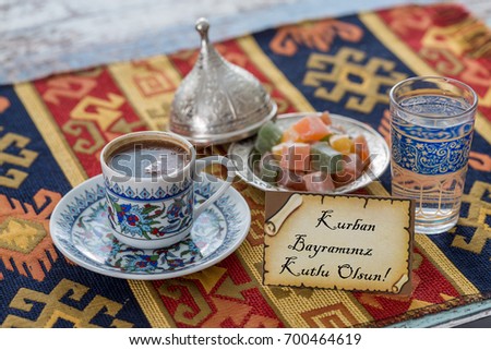 Happy eid al adna text in turkish on greeting card with turkish coffee, delights on traditional tablecloth