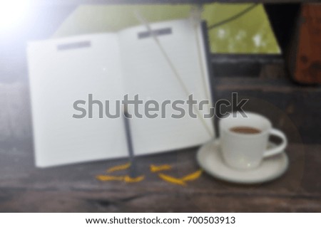 blur coffee cup on wooden background with note book ,Vintage tone filter effect color style