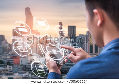 The abstract image of business man point to the hologram on his smartphone and blurred cityscape is backdrop. the concept of communication, network, cloud, internet of things and technology.