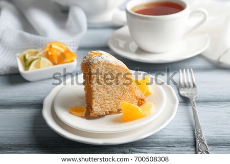 Plates with delicious cake and sliced citrus fruits on wooden table