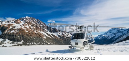 Helicopter landing on snow mountain in tasman glacier in Mt Cook, New Zealand. The helicopter service in Mt Cook offers scenic flights, glacier landing and emergency rescue. Royalty-Free Stock Photo #700522012