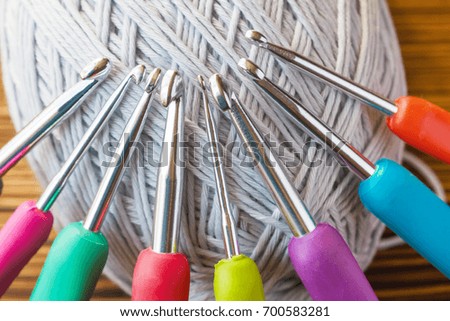 Gray yarns for crocheting and a set of multicolored hooks. Close-up, selective focus