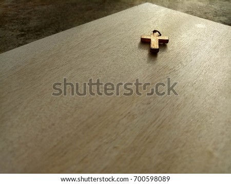 Old Christian Cross placed on wooden floor with morning sunlight, selective focus with copy space