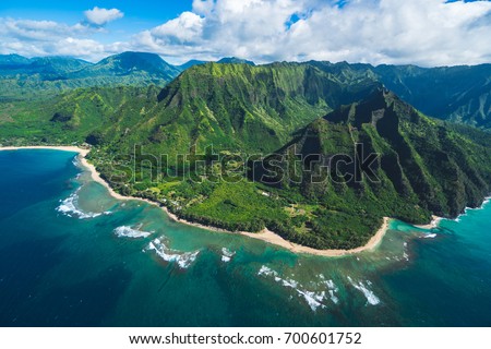 Perfect view of the east side of Kauai, Princeville area from a helicopter with lush green mountain and garden in the background, ocean in the foreground