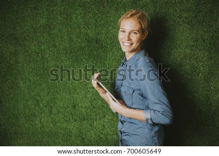 Pretty young woman with tablet by the green wall