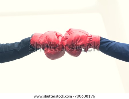 Close up of young businessman and businesswoman wear boxing gloves making a fist bump on modern building background. Businesspeople wear suit with combat glove do a fist pump together after good deal. Royalty-Free Stock Photo #700608196