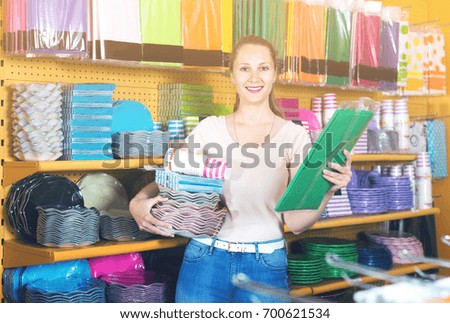 Female is holding kitchen accessories in shop. 