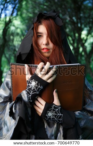Portrait of witch in cloak with book
