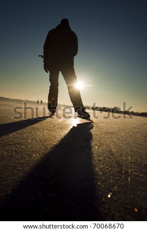 Ice skater at sunset on a frozen lake.