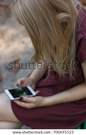 Young attractive woman at the park, she is texting with her smartphone